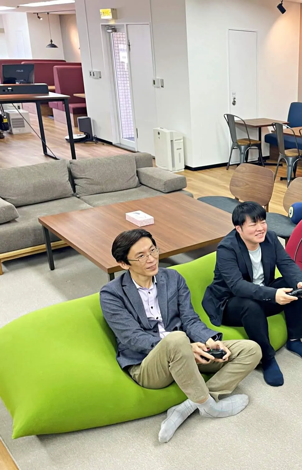 オフィスのラウンジで、ビーズクッションに座ってゲームを楽しむキャプサーの社員2名